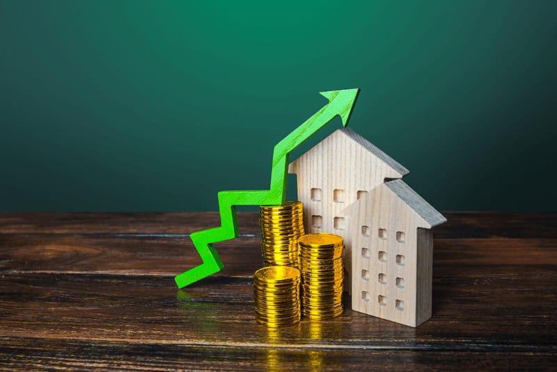 green arrow rising up above wooden houses and stacks of gold coins