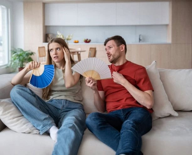 Couple sitting on couch holding fans